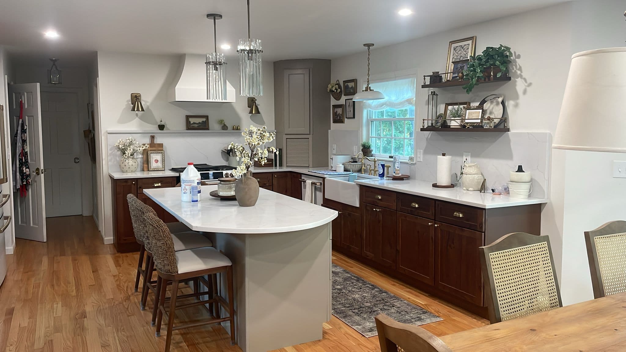 Kitchen featuring a white marble island, dark wood cabinets, farmhouse sink, and open shelving.