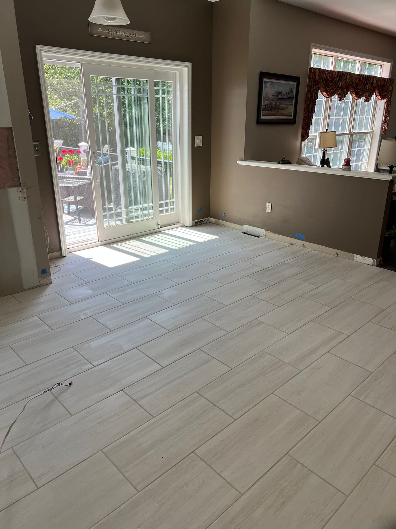 Light wood look tile flooring in a room with brown walls and sliding doors.